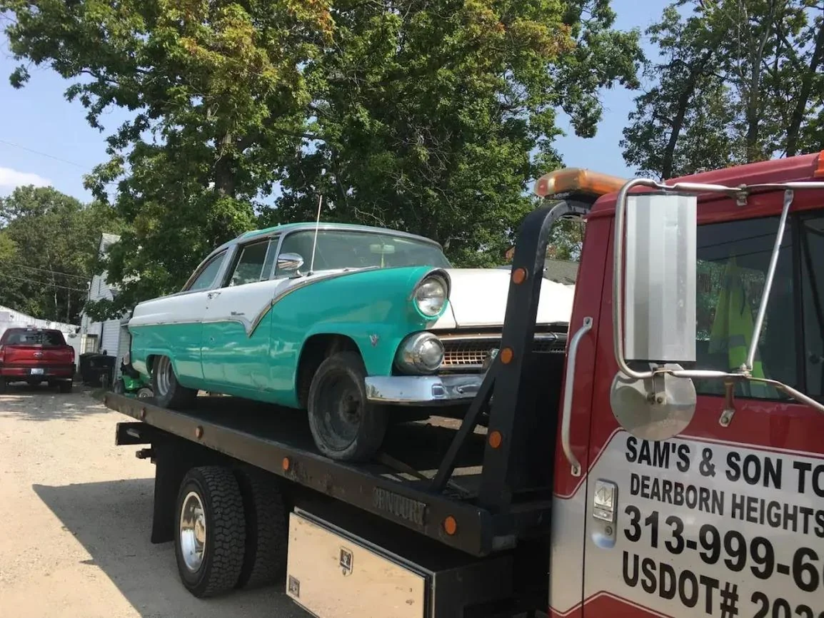 Turquoise and white classic car being transported on the flatbed